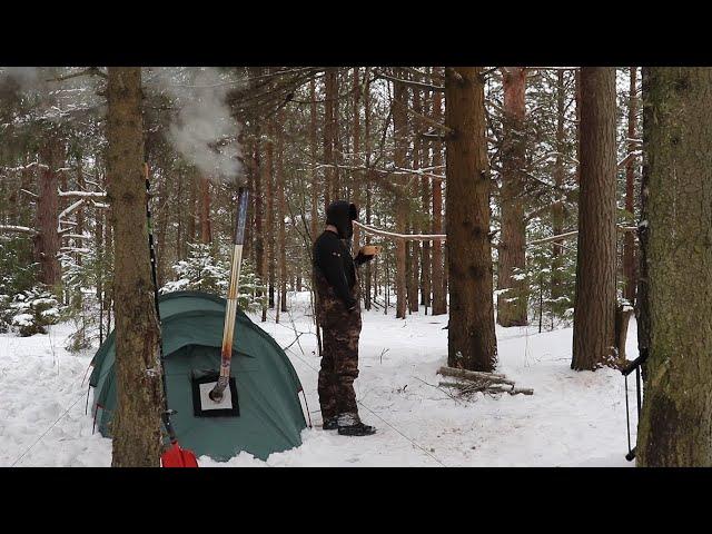 Одиночный зимний поход с ночевкой в горячей палатке в снежном лесу.