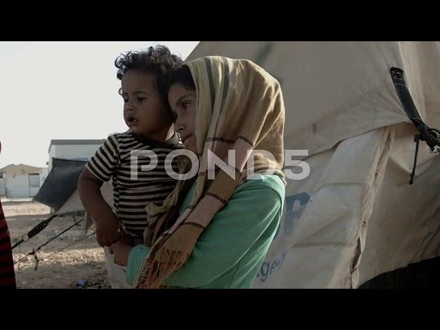 young syrian girl and her little brother standing in zaatari camp