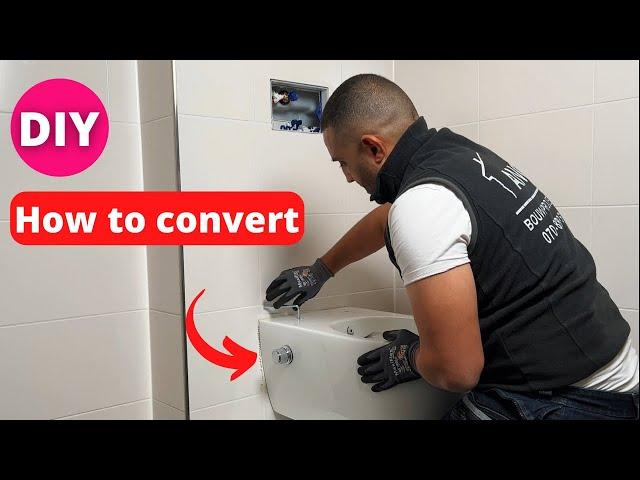 A plumber shows  an existing wall toilet into a toilet with toilet shower.