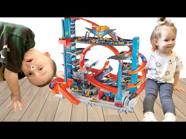 Stefania and Danya are playing in the big garage of Hot Wheels Ultimate with cars.