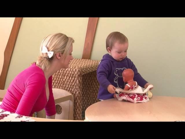 Connecting with Practice NQS PLP - A very young child putting a bib on a doll