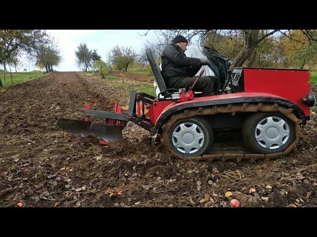 Гусеничный минитрактор пашет двух корпусным плугом.