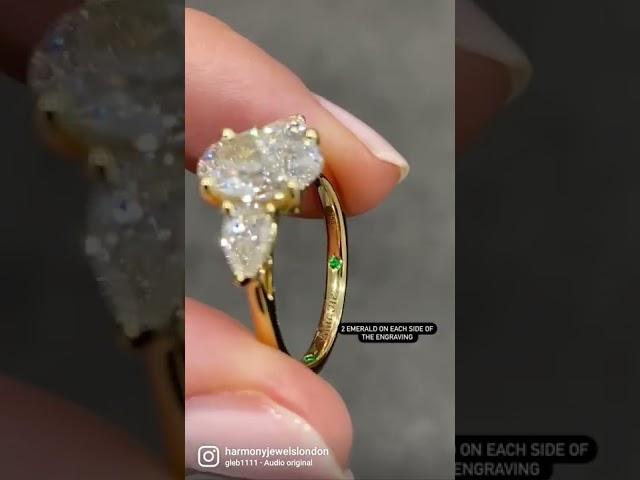 2ct oval trilogy ring with 0.28ct pear cut sides and 2 emerald stones on each side of the engraving