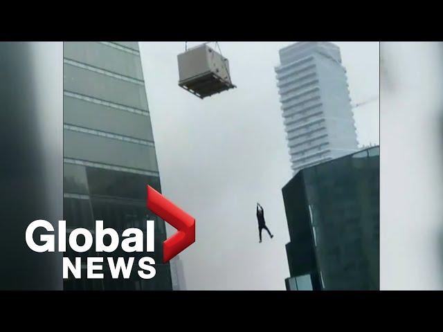 Construction worker seen dangling from crane in Toronto