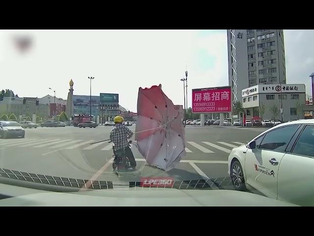 Mopedist catches flying umbrella