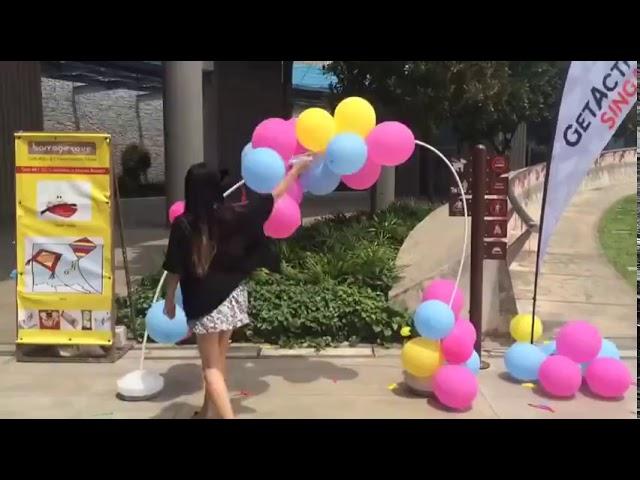 Girl Popping a Balloon Arch Outdoors