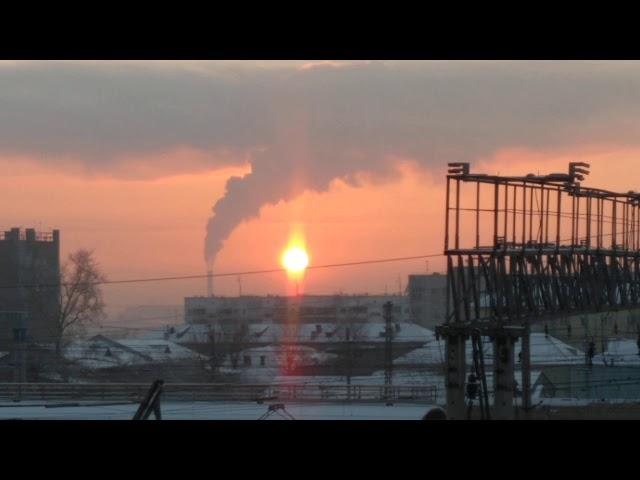 Закат солнца в Новосибирске, пригородный ж/д вокзал и серый город.