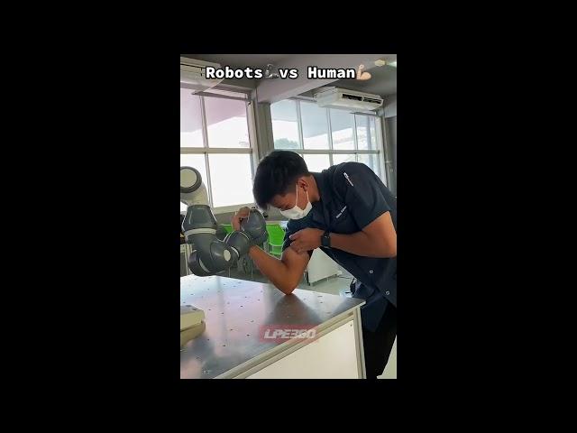 Guy arm wrestles against robot arm