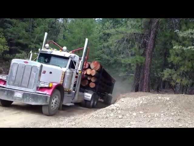 Two log trucks coming over a hill