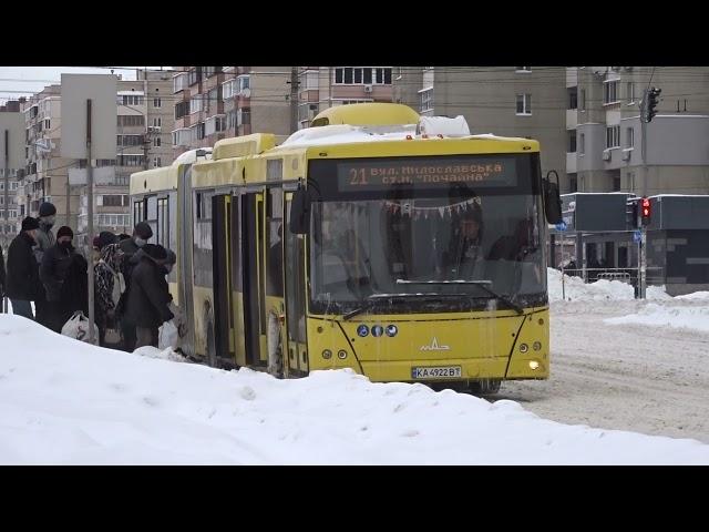 Bus MAZ 215 in winter Kyiv, at a stop. Passengers board. A huge yellow bus