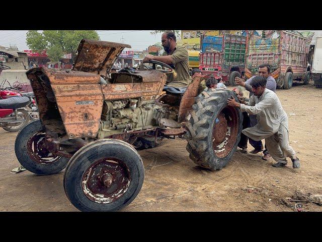 An expert mechanic repairs a rusty tractor that has been left in the rain for years