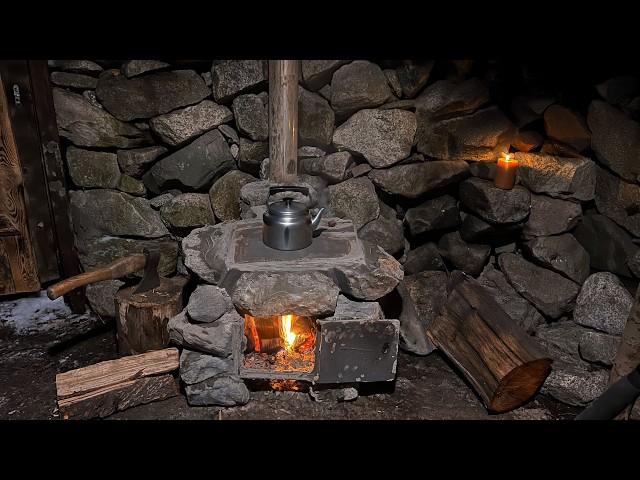 A man restores a stone hut in the mountains. Builds a fireplace. Overnight in solitude.