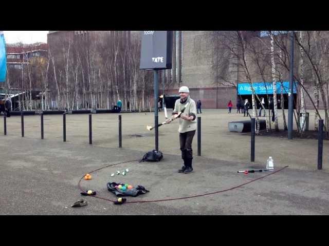 A juggler is playing with fire near Tate Modern, London.