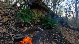 Bau einer warmen und gemütlichen Überlebenshütte an den Wurzeln einer umgestürzten Eiche. Bushcraft