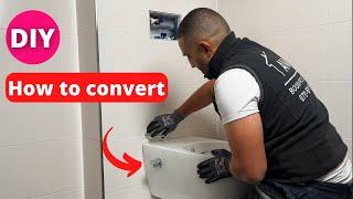 A plumber shows  an existing wall toilet into a toilet with toilet shower.