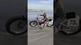 Biker girl playing in the sand on her motorcycle