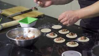 Cook putting minced meat on dough. Art. Close-up of professional chef applying minced meat for