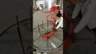 Shaping a red hose: people coiling a red hose with a machine