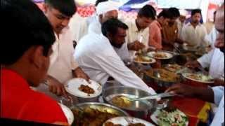 Men grabbing food at a wedding reception in Pakistan