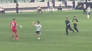 A Chinese fan enters the playing field and greets Dibu Martinez