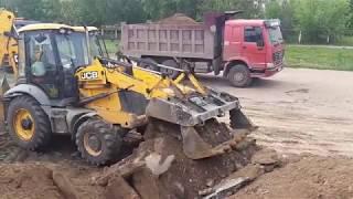 Погрузка грунта экскаватором-погрузчиком JCB в самосвалы