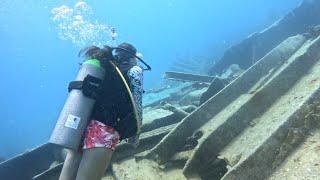 Female Scuba Diver Swims along Shipwreck