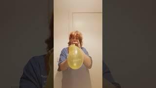 blowing up a yellow curly balloon