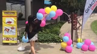 Girl Popping a Balloon Arch Outdoors