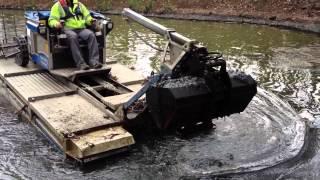 Truxor with the clamshell attachment removing silt from a pond