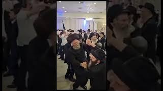 Two Hasidic men dancing by a Jewish wedding