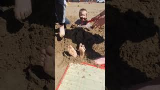 trying to get the boy out of the sand on the beach!