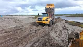 Сочлененный  самосвал Volvo A35F выползает из обводненного песка