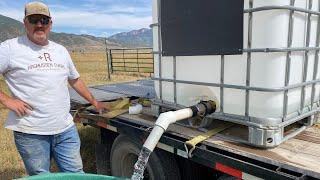 Refilling cattle trough in pasture with no water.