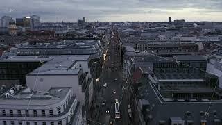 Traffic in long straight street in urban borough. Tilt up reveal cityscape and cloudy sky. Dusk in