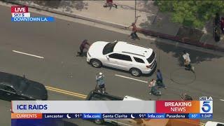 Protester tries to stop ICE SUV from leaving site of raid in L.A.