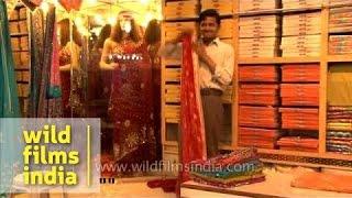 Salesman showing off intricate wedding saree in a shop - Varanasi