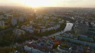 Fly above residential urban borough along river. Aerial panoramic view of city at sunset. Berlin