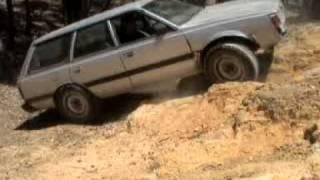 subaru with modified landcruiser rims climbing a rocky hill