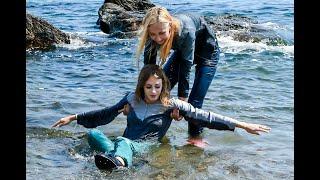 two pretty girls friends pose brightly in wet clothes on the seashore for wetlook video