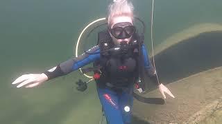 Blonde female scuba diver girl explore sunken wreck and Dinosaur underwater, neoprene diving suit