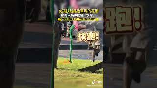 女孩扶起路邊草坪的花灑，被路人高聲提醒「快跑」