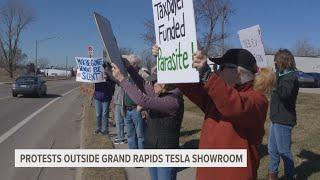 Dozens gather outside Tesla showroom in Grand Rapids to protest Musk, DOGE