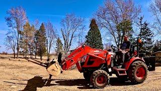 Kioti CX2510 Tractor doing chores with fork attachment