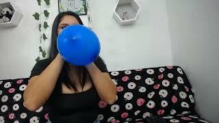 Girl blowing a blue heart balloon