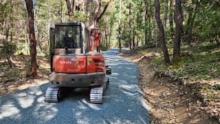 Culvert and truck spreading gravel on the new road Kubota KX 040 4