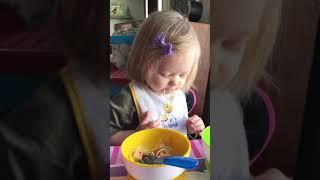 Little  girl struggles eating a spaghetti noodle.