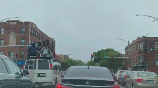 Jesse White tumblers seen riding on van roof