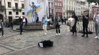 Street musicians sing at Rynok Square in Lviv. A sign reads "30% for the Armed Forces of Ukraine"