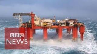 Huge waves crash against swaying North Sea oil rig