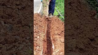 The process of manually digging a drainage ditch with an iron hoe